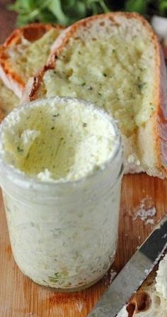 bread and butter on a cutting board with a knife next to the spread in a jar