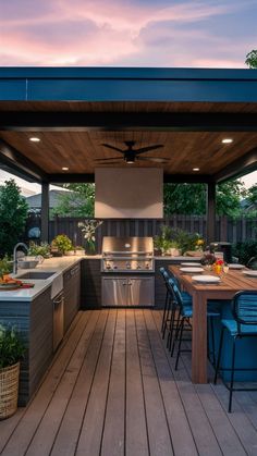 an outdoor kitchen and dining area is lit up by the sun set over the grill