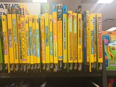 there are many children's books on the shelf in the library and one is yellow