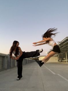 two people are jumping in the air with their skateboards on an empty parking lot