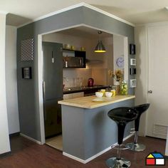 a kitchen with an island and bar stools in the middle, next to a refrigerator