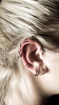 a woman with long blonde hair and piercings on her ear