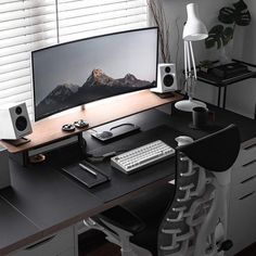 a desk with a monitor, keyboard and speakers on it