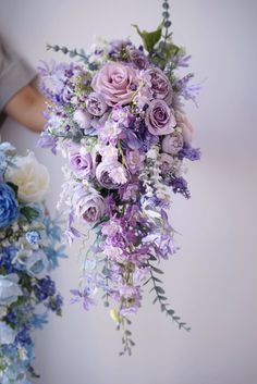 a bouquet of purple and white flowers is being held by someone