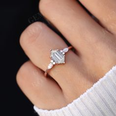 a woman's hand with an engagement ring on it, showing the center stone