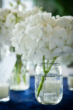 white flowers are in vases on a table