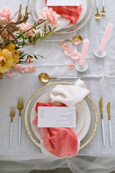 the table is set with pink and white napkins, silverware, and gold place settings