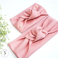 two pink bow headbands on top of each other with flowers in the background