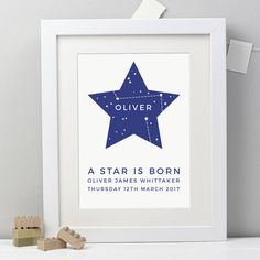 a star is born birth print in white frame next to wooden blocks and a toy