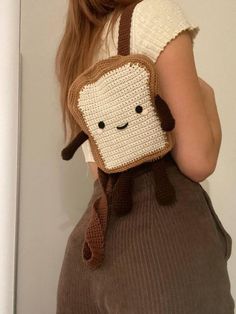 a woman is holding a crocheted bag with a face on it