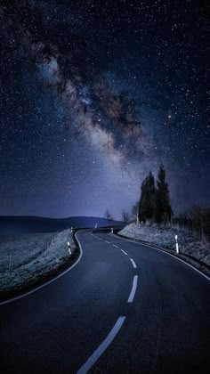 the night sky is filled with stars, and there are no cars on the road