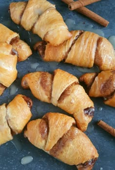 several croissants wrapped in cinnamon and sitting on a blue surface with two cinnamon sticks sticking out of them