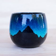 a blue and black cup sitting on top of a wooden table