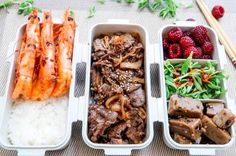 three trays filled with different types of food next to chopsticks and strawberries