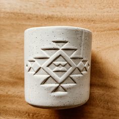 a white ceramic cup sitting on top of a wooden table