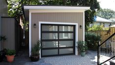 a garage with an open door and plants in pots on the side of the building