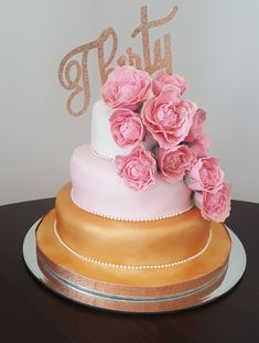 a three tiered cake with pink flowers on top and the word party spelled in gold