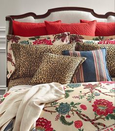 a leopard print comforter and pillows on a bed with red trim around the headboard