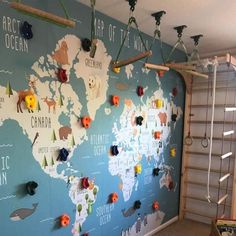 a world map is hanging on the wall in a children's room with wooden ladders