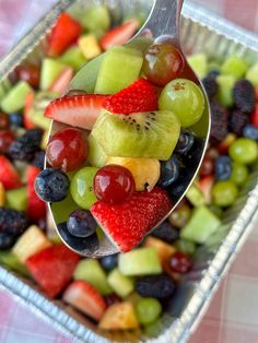 a spoon full of fresh fruit salad on a table