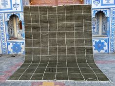 an area rug with blue and white tiles on the ground in front of a building