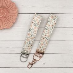 a pair of flowered lanyards on a white wooden table with a pink fan