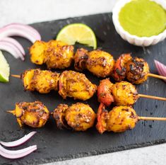 grilled chicken skewers with cilantro sauce and onions on a slate board