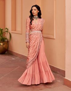 Introducing this enchanting peach sharara sari, crafted on a georgette base for a graceful drape. Paired with a printed hand-embroidered blouse and a chic belt, this ensemble embodies elegance with a contemporary twist. Make a statement at any event with this sophisticated fusion of style and tradition. Sharara And Blouse, Traditional Drape Palazzo Set With Unstitched Blouse, Wedding Outfits For Women Indian, Elegant Designer Peach Anarkali Set, Elegant Peach Anarkali Set For Designer Wear, Anarkali Style Floor-length Peach Sharara, Anarkali Style Peach Floor-length Sharara, Floor-length Peach Anarkali Sharara, Designer Peach Dress With Traditional Drape