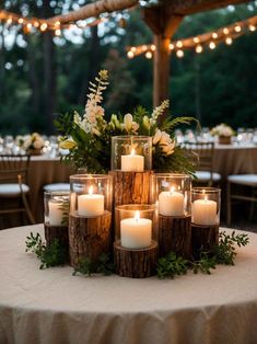 the centerpiece is made out of logs with candles and greenery in them for a rustic look