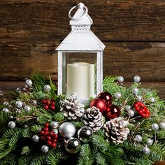 a candle is sitting on top of a christmas wreath with pine cones and ornaments around it