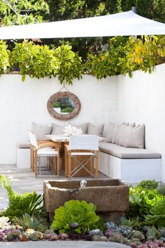 an outdoor living area with couches, tables and plants on the side of it