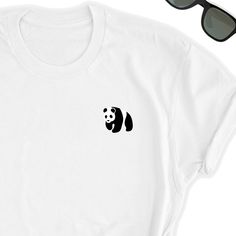 Panda Shirt // Cute Panda T-Shirt // Panda Bear Tee // Panda Top // Panda Tee // Unisex Panda Bear Tee Love Pandas? Who doesn't? Take this beautiful simple Panda icon design to your side everywhere. Friends will love it! This t-shirt feels soft and lightweight, with the right amount of stretch. It's comfortable and flattering for both men and women. * 100% combed and ring-spun cotton (heather colors contain polyester) * Fabric weight: 4.2 oz (142 g/m2) * Shoulder-to-shoulder taping * Side-seamed White Shirt With Funny Print For Everyday, Everyday White Shirt With Funny Print, White T-shirt With Funny Print For Everyday, Simple White Tops With Graphic Print, Simple White Graphic Print T-shirt, Simple White T-shirt With Graphic Print, Casual White Print T-shirt For Everyday, Casual White Printed T-shirt For Everyday, White Basic T-shirt With Funny Print