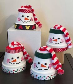 three snowmen with hats and scarves on top of each other in front of a box