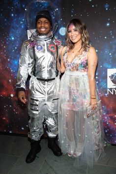 a man and woman in space suits posing for a photo on the red carpet at an event