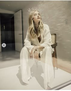 a woman is sitting on a chair in front of a glass wall and looking up at the sky