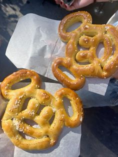 two pretzels sitting on top of wax paper next to some other food items