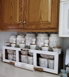 some jars are stacked on top of each other in front of a microwave and cabinets