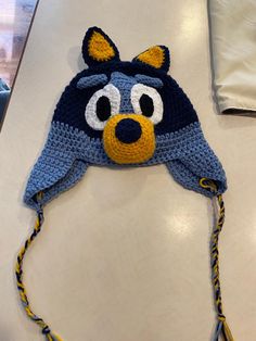 a crocheted hat with an animal face on it sitting on a counter top