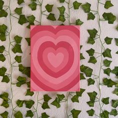 a card with a heart on it surrounded by green leaves and ivy growing up the wall