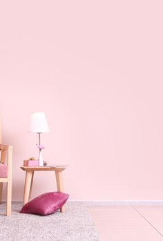 a pink room with two wooden chairs and a small table on the floor in front of it