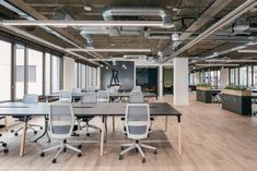 an empty office with desks and chairs in the center, along with large windows