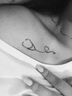 a woman with a heart tattoo on her chest holding the hand of another person's arm