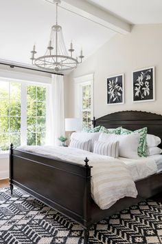 a bedroom with a large bed, chandelier and two pictures on the wall