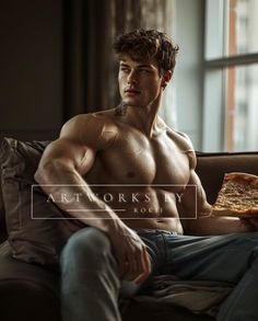 a shirtless man sitting on a couch holding a pizza