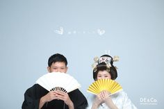 two people dressed in traditional japanese garb and holding fans