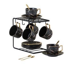 a set of four black and gold coffee cups on a metal rack with matching saucers and spoons