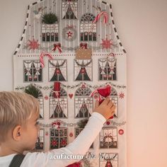 a young boy decorating a house with candy canes and christmas decorations on the wall