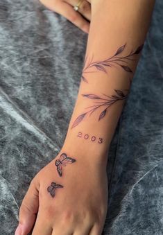 a woman's hand with a tattoo on it that reads 200 and has leaves