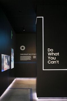 an exhibit room with black walls and white lettering on the wall that says do what you can't