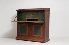 an old wooden cabinet with green glass doors on the top and bottom, sitting against a white wall